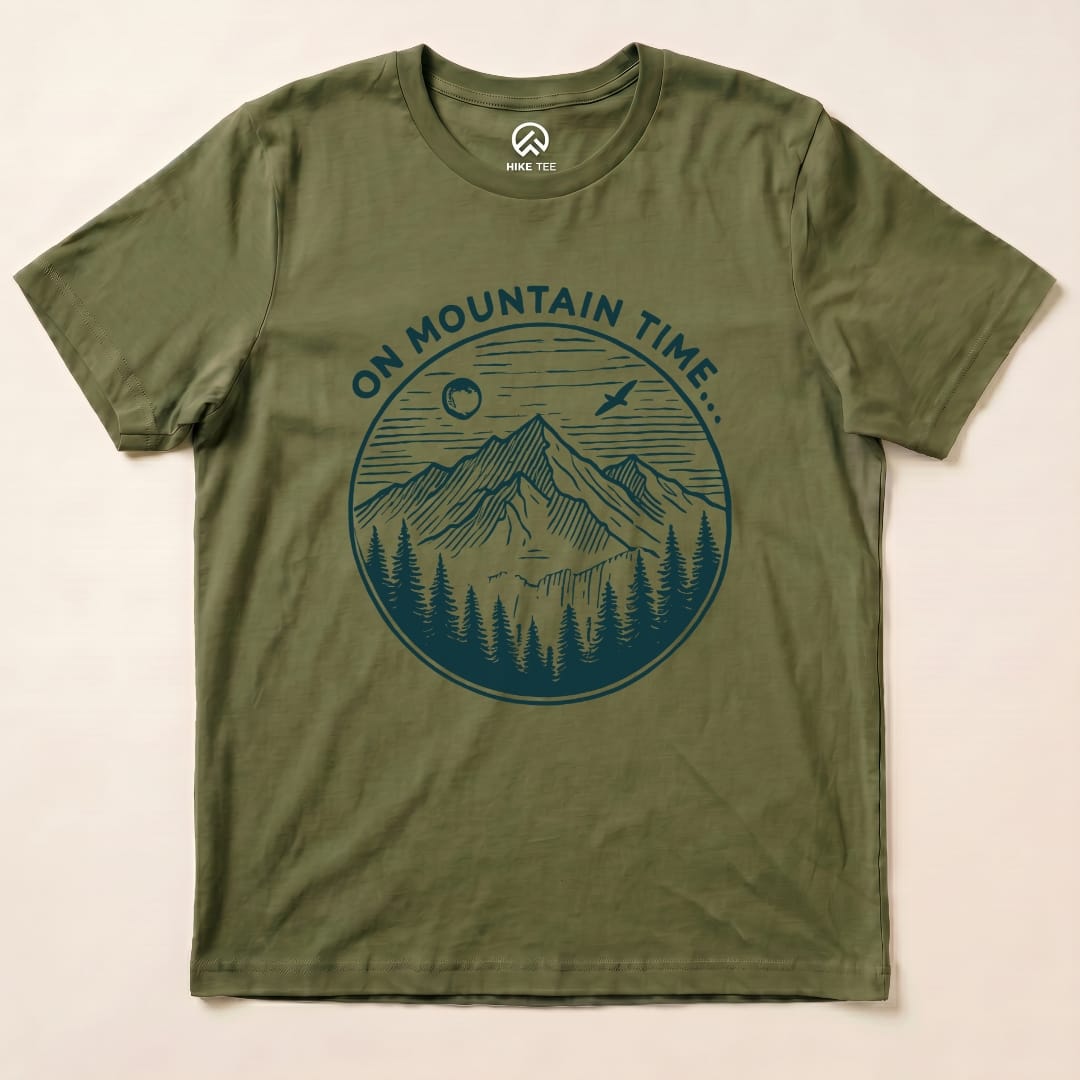 The olive green graphic t-shirt features a mountain landscape design with the text "ON MOUNTAIN TIME..." encircling the image.