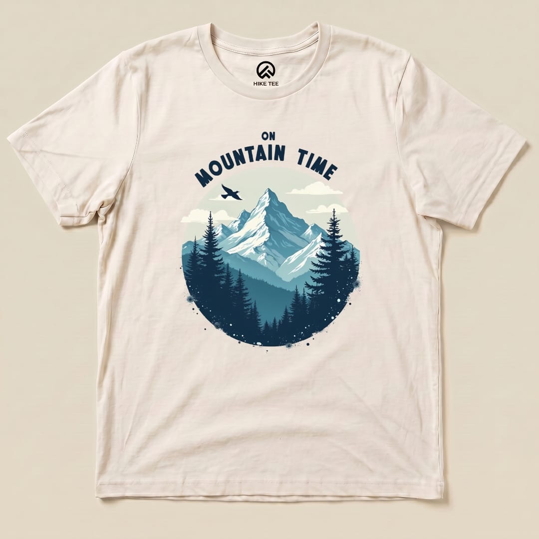 A flat graphic t-shirt featuring a mountain scene with the text "On Mountain Time" above a forest landscape.