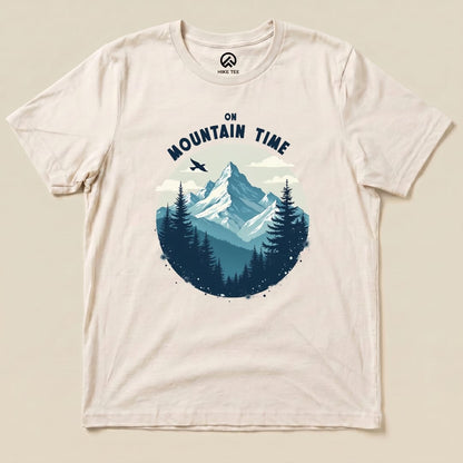 A flat graphic t-shirt featuring a mountain scene with the text "On Mountain Time" above a forest landscape.