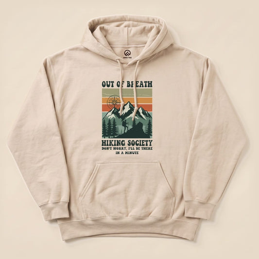 A light beige "Out of Breath Hiking Society Hoodie" features a graphic of mountains and trees with the slogan 'Don't worry, I'll be there in a minute.
