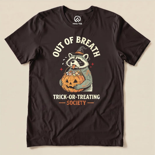 A graphic t-shirt featuring a raccoon holding a pumpkin bucket filled with candy, titled "Out of Breath Trick-or-Treating Society.