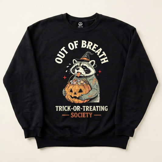 A graphic sweatshirt featuring a raccoon holding a pumpkin filled with candy, with the slogan "Out of Breath Trick-or-Treating Society".