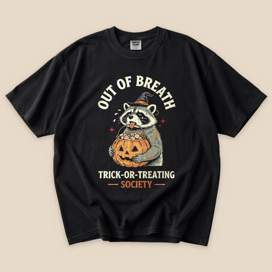 The graphic t-shirt features a raccoon wearing a witch hat, holding a pumpkin full of candy with the words "Out of Breath Trick-or-Treating Society" above.