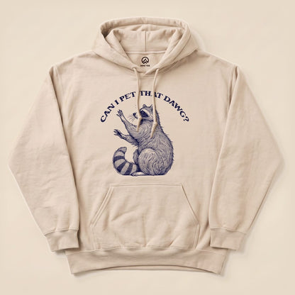 A beige hoodie featuring a graphic of a raccoon with the text "CAN I PET THAT DAWG?" printed above, showcasing the Pet That Dawg Raccoon Hoodie design.