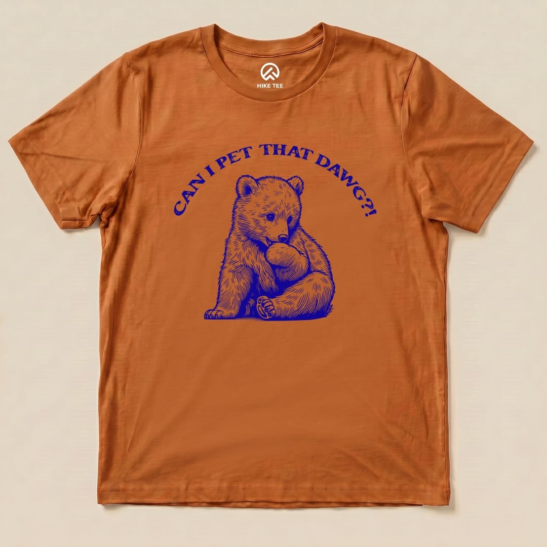 A graphic t-shirt in orange featuring a bear cub with the text "CAN I PET THAT DAWG?!" in blue above it.