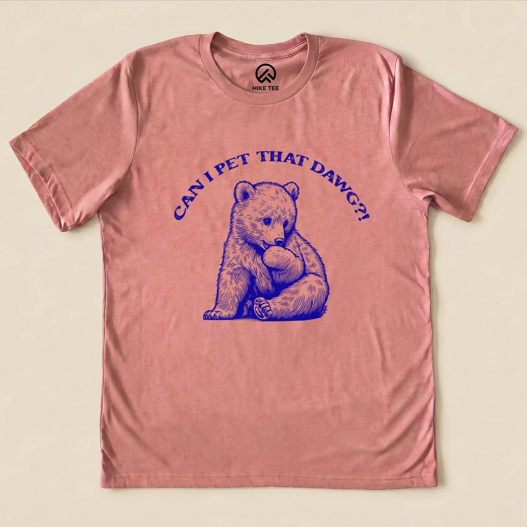 A pink graphic t-shirt featuring a cute bear illustration and the text "CAN I PET THAT DAWG?!".