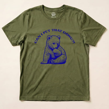 A graphic t-shirt featuring a playful bear illustration and the text "CAN I PET THAT DAWG?!" on an olive green background.