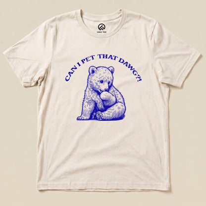 The "Pet That Dawg Shirt" features a blue graphic of a playful bear cub with the text "CAN I PET THAT DAWG?!" above it on a cream t-shirt.