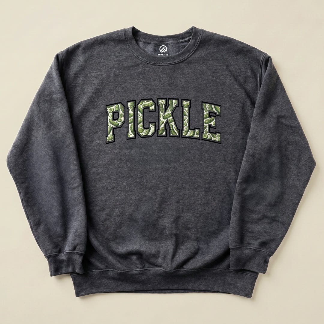 A dark gray sweatshirt featuring the word "PICKLE" in bold green, pickle-patterned letters, representing the Pickle Camping Sweatshirt design.