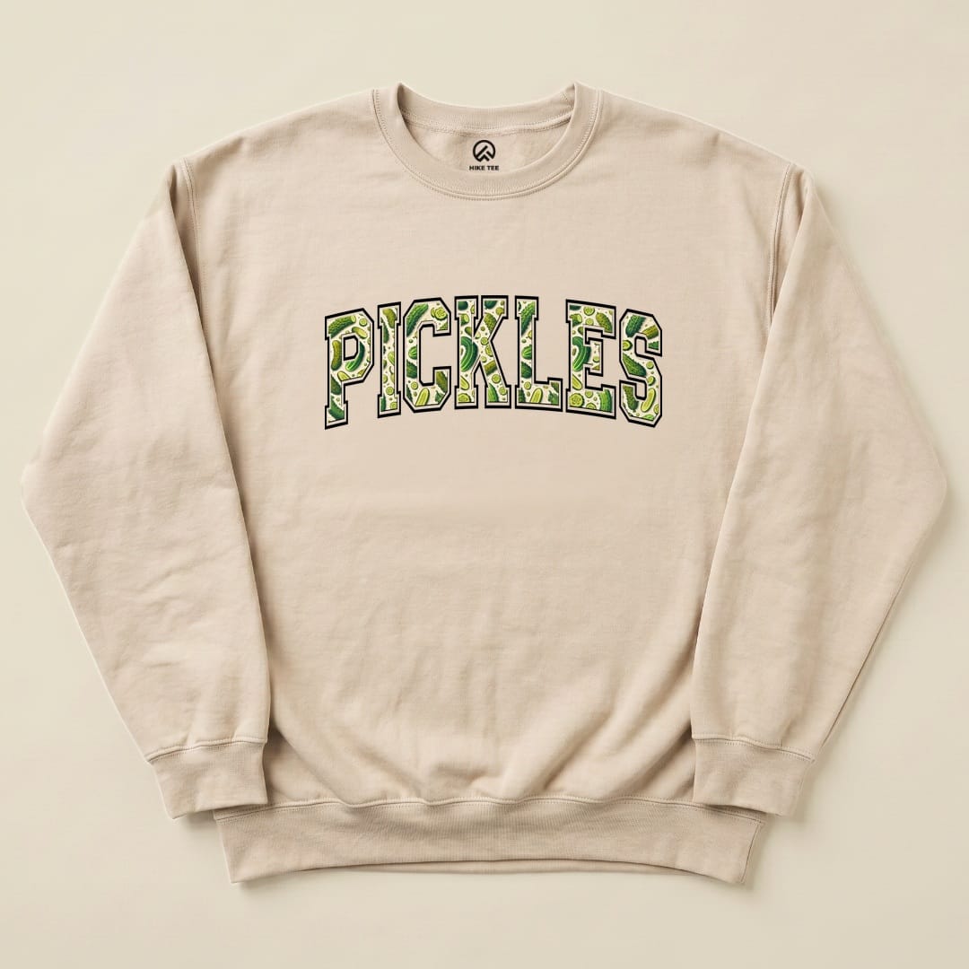 A beige "Pickles Sweatshirt" features the word "PICKLES" in bold, green lettering with a textured design, laid flat on a neutral background.