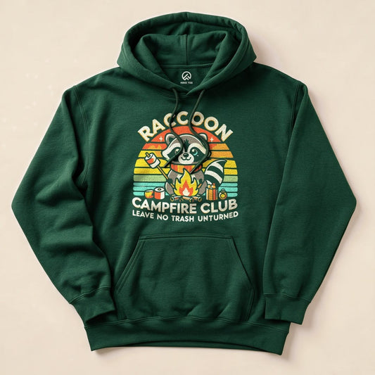 Graphic green hoodie featuring a raccoon holding food by a campfire with the words "Raccoon Campfire Club" and slogan "Leave No Trash Unturned".