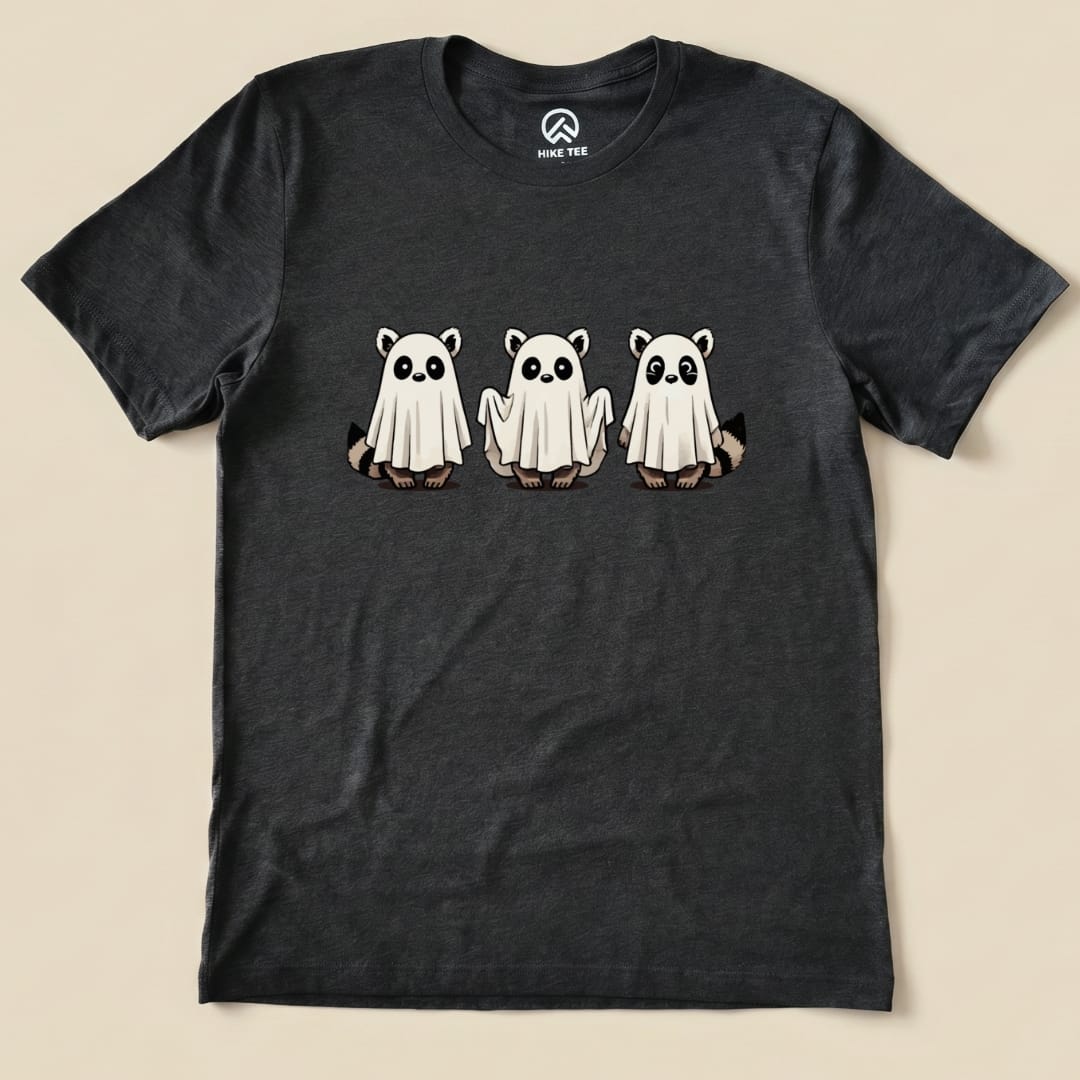 The graphic t-shirt features three playful raccoons dressed as ghosts, highlighted against a dark background.