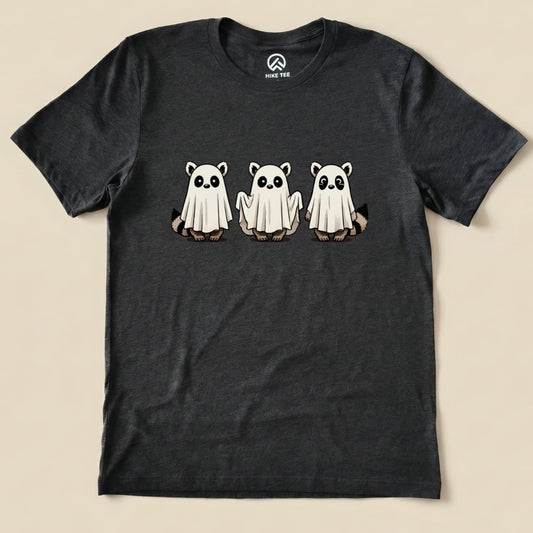 The graphic t-shirt features three playful raccoons dressed as ghosts, highlighted against a dark background.