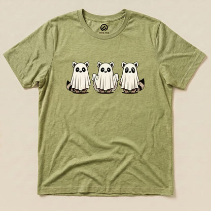 A graphic t-shirt featuring three cartoon raccoons dressed as ghosts on a light green background, labeled as the "Raccoon Ghosts Shirt.