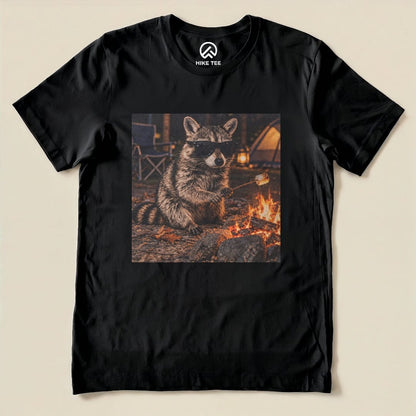 A graphic t-shirt featuring a raccoon in sunglasses sitting by a campfire, ready to roast marshmallows.