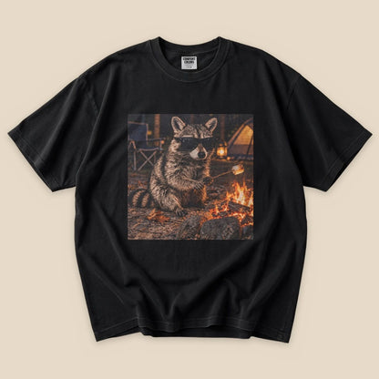 A black graphic t-shirt featuring a raccoon in sunglasses sitting by a campfire, holding a marshmallow on a stick.