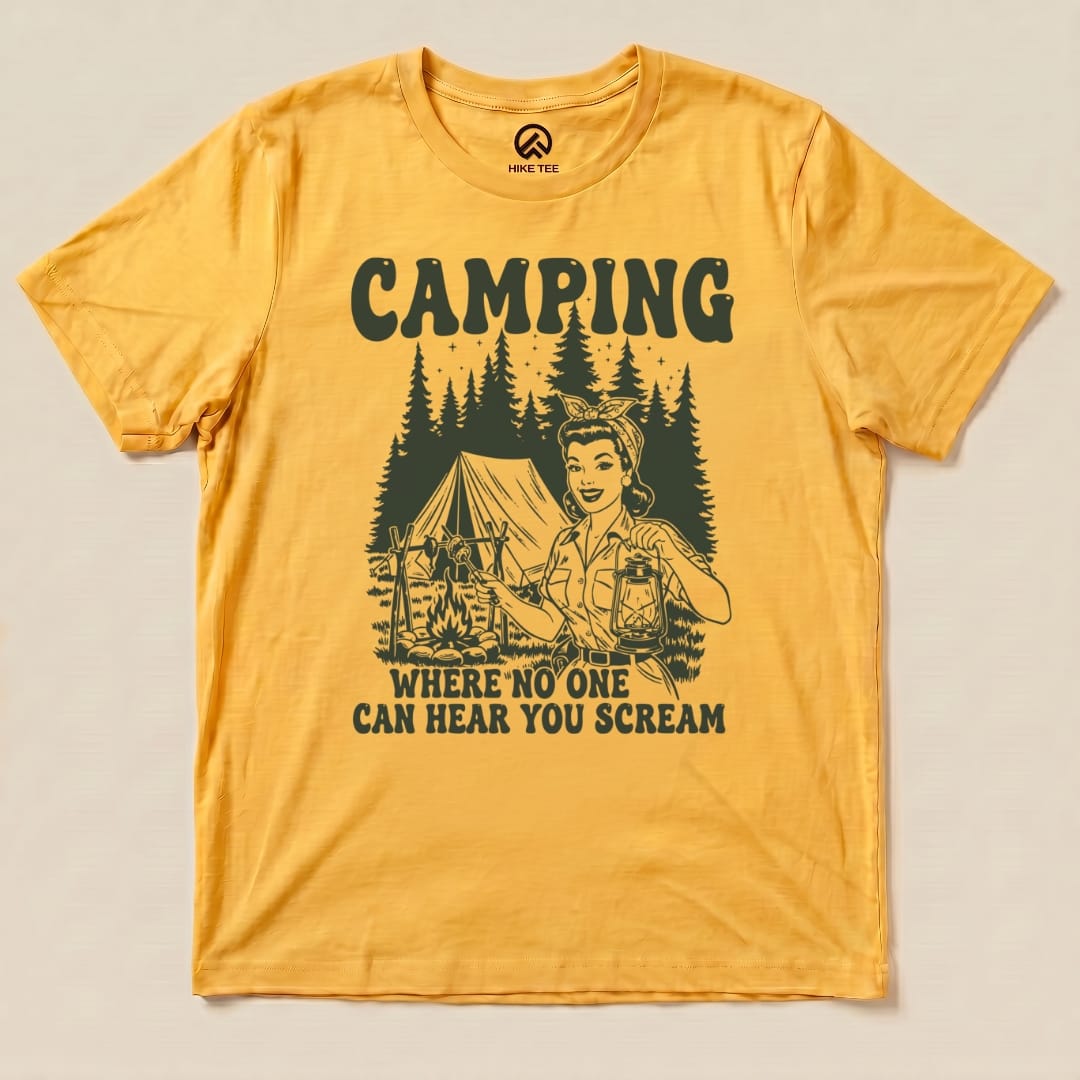 A flat lay of a graphic t-shirt featuring the slogan "CAMPING WHERE NO ONE CAN HEAR YOU SCREAM" alongside a retro camping scene.