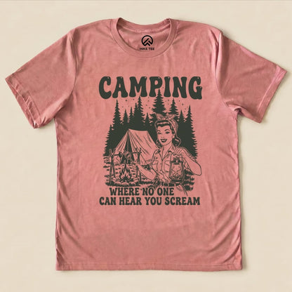 A graphic t-shirt featuring a retro design with the text "CAMPING WHERE NO ONE CAN HEAR YOU SCREAM" and an illustration of a woman holding a lantern near a tent.