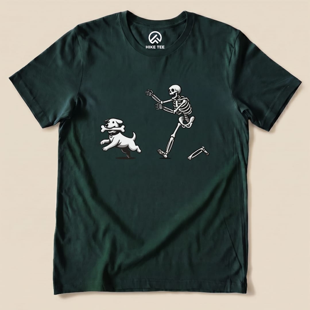 A dark green graphic t-shirt features a playful skeleton chasing a white dog with a bone, highlighting the Skeleton and Dog Shirt design.