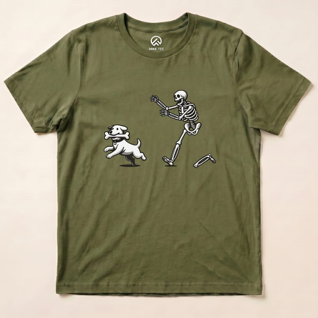 A graphic t-shirt featuring a playful skeleton and dog running together, showcasing the "Skeleton and Dog Shirt" design on an olive green background.