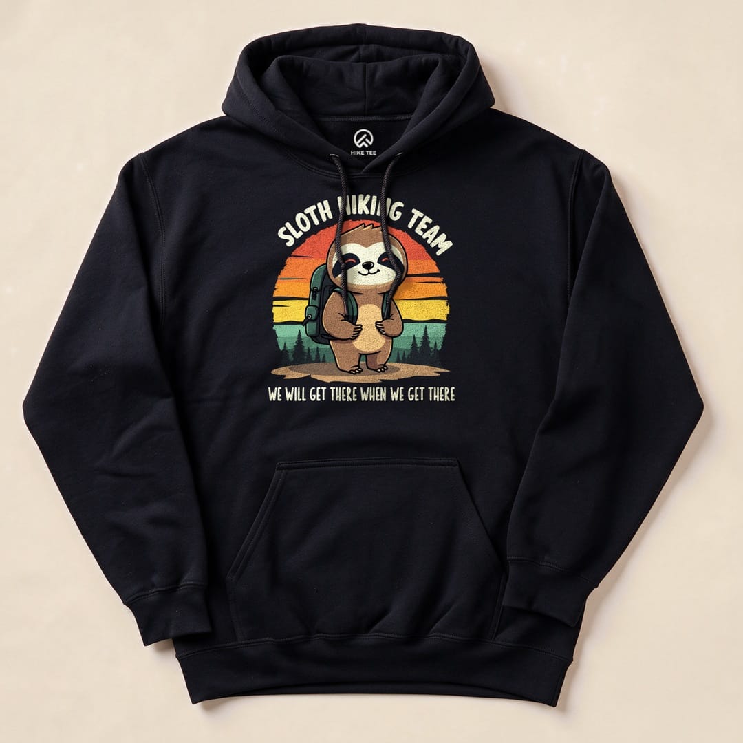 A graphic t-shirt features a sloth with a backpack against a sunset, labeled "Sloth Hiking Team" with the slogan "We will get there when we get there.