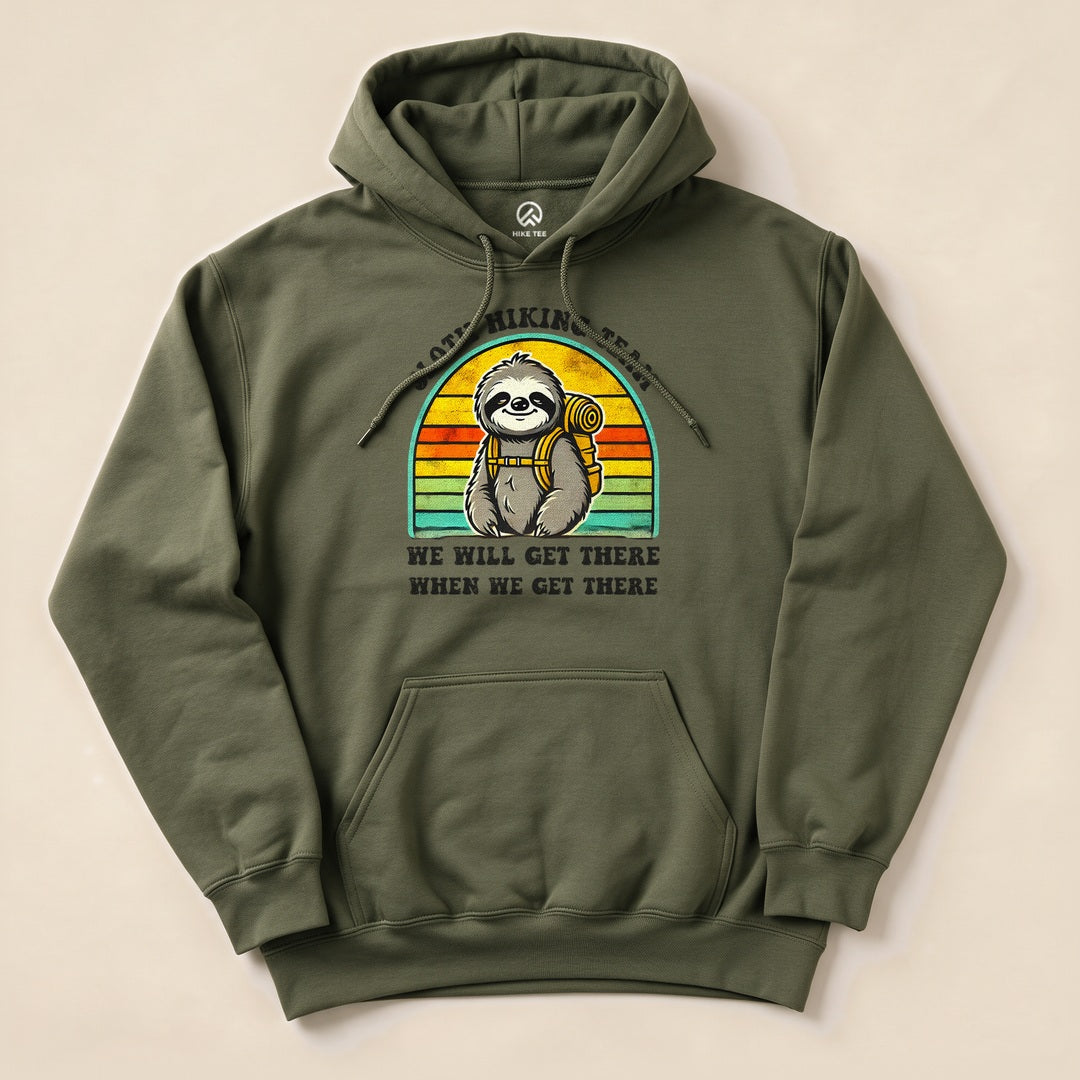 A graphic t-shirt featuring a sloth with a backpack against a retro sunset background, stating "WE WILL GET THERE WHEN WE GET THERE.