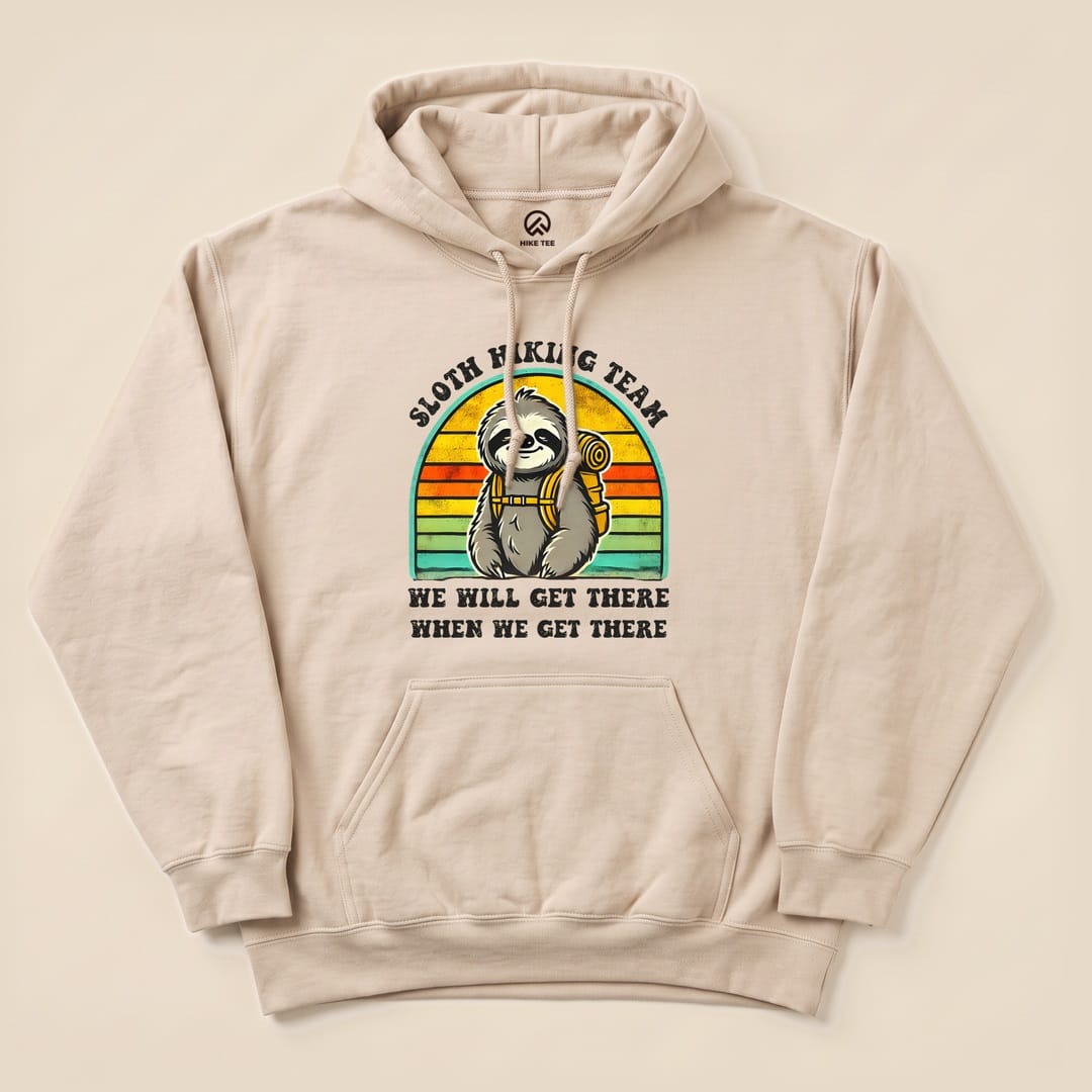 The "Sloth Hiking Team Retro Sunset Hoodie" features a cartoon sloth with a backpack, set against a colorful sunset background and the text "WE WILL GET THERE WHEN WE GET THERE.