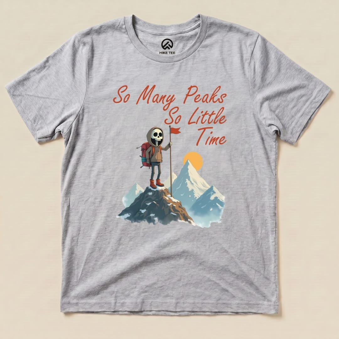 The graphic t-shirt features a skeleton hiker holding a flag on a mountain peak with the slogan "So Many Peaks So Little Time.