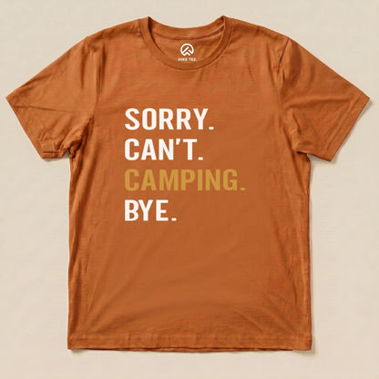 A flat lay of an orange graphic t-shirt featuring the slogan "Sorry. Can't. Camping. Bye." printed in bold text.
