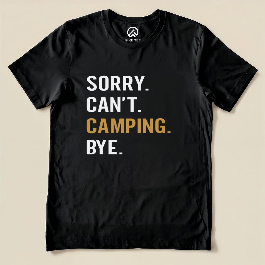 A flat black graphic t-shirt features the text "Sorry. Can't. Camping. Bye." in bold white and gold lettering.