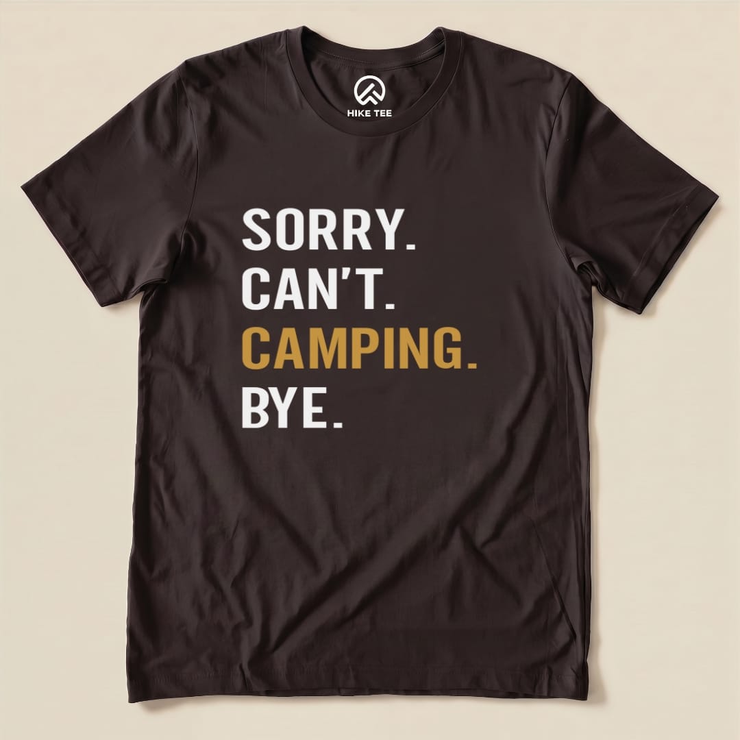A graphic t-shirt in dark brown features the phrase "Sorry. Can't. Camping. Bye." in bold white and gold lettering.