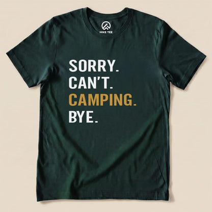 A graphic t-shirt in dark green featuring the slogan “Sorry. Can’t. Camping. Bye.” prominently printed in bold letters.