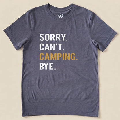 Graphic t-shirt featuring the slogan "Sorry. Can't. Camping. Bye." printed in bold white and gold letters on a gray fabric.