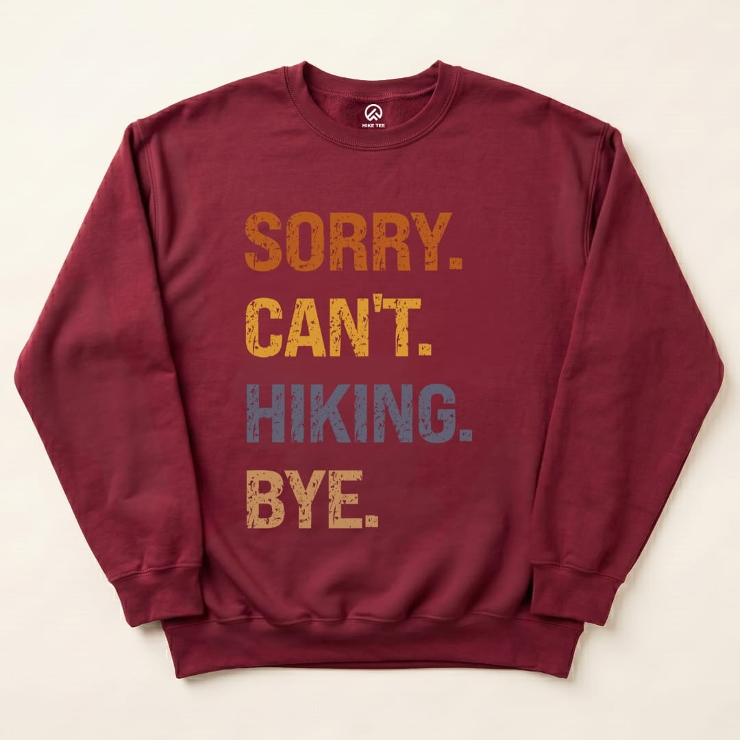 A maroon sweatshirt featuring the slogan "Sorry. Can't. Hiking. Bye." in bold, distressed fonts, showcasing a funny outdoor theme.
