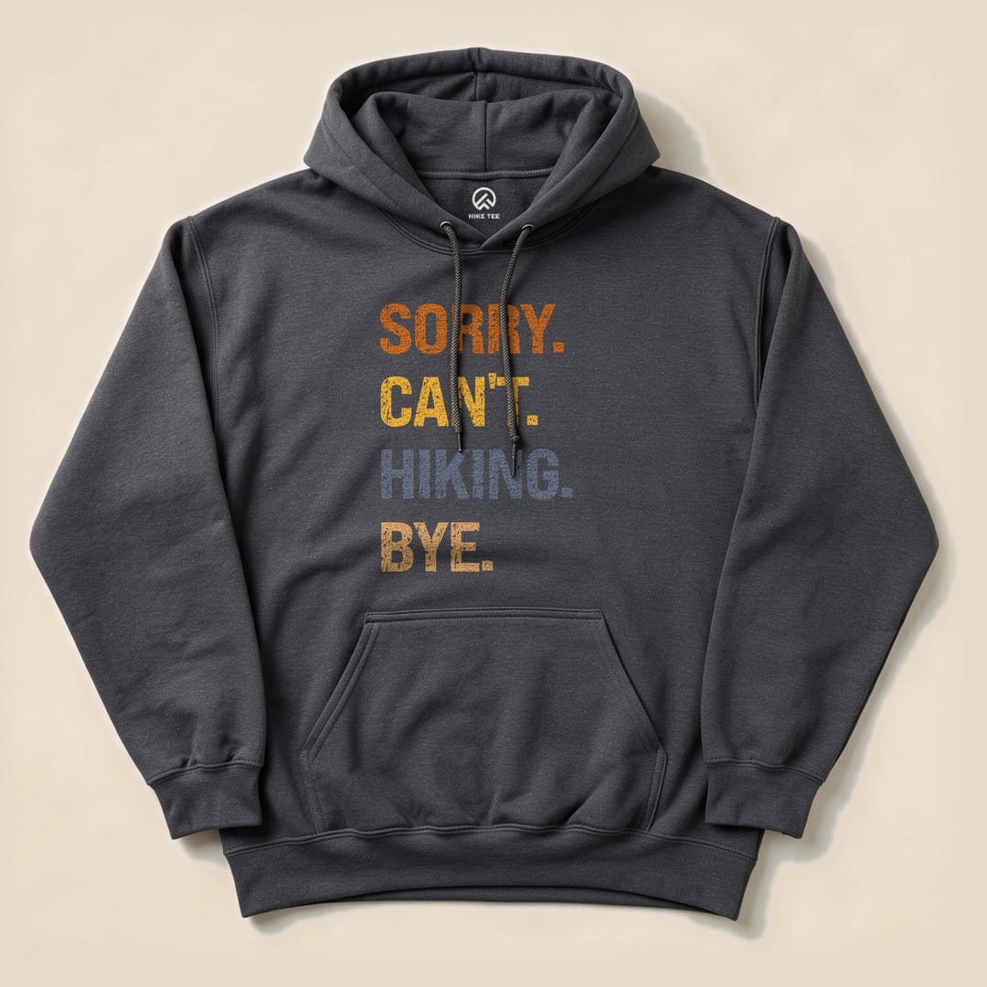 A dark gray hoodie featuring a graphic design with the phrase "Sorry. Can't. Hiking. Bye." in bold, colorful letters.