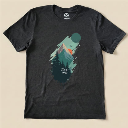 The Stay Wild Shirt features a graphic design of mountains, trees, and a sunset with the slogan "Stay Wild" prominently displayed.