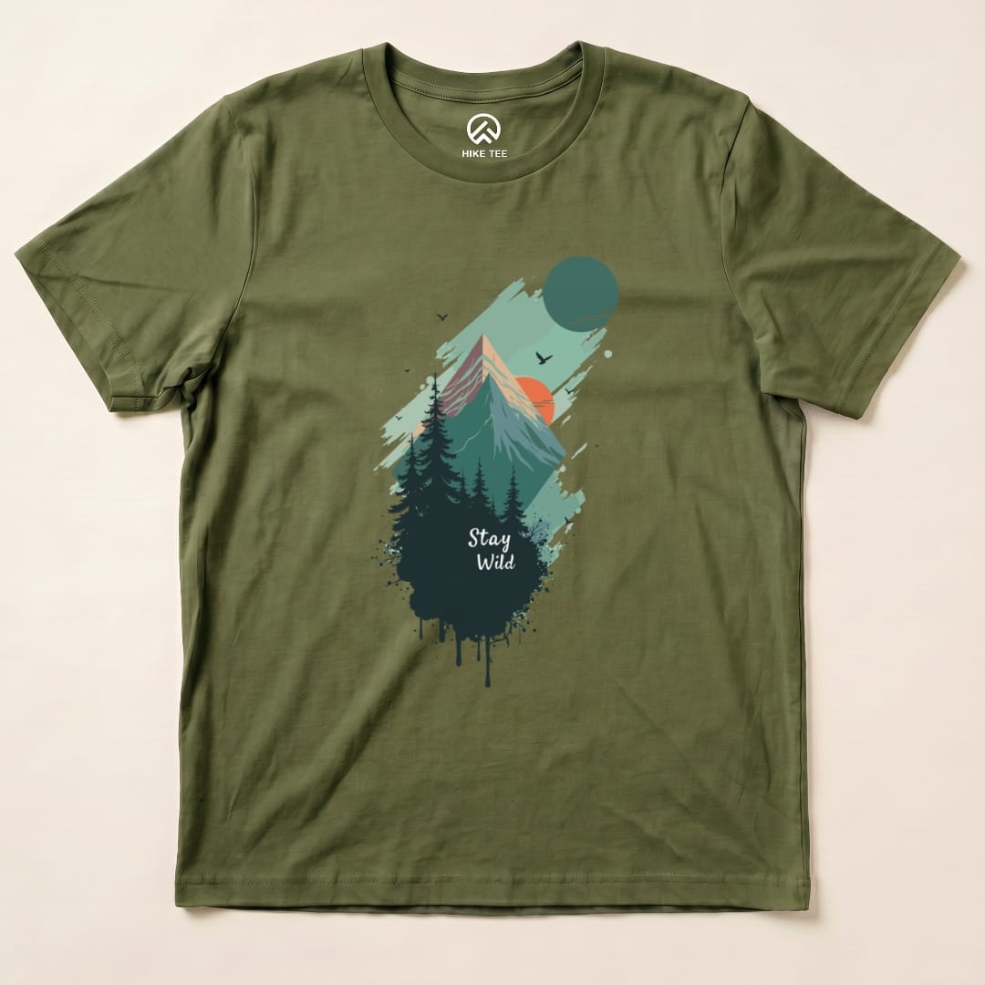 The Stay Wild Shirt features a mountain and forest graphic with vibrant colors and the phrase "Stay Wild" prominently displayed.