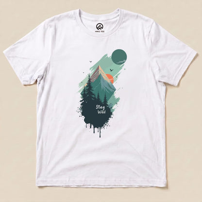 A flat white graphic t-shirt features a colorful mountain landscape and the text "Stay Wild" beneath evergreen trees.