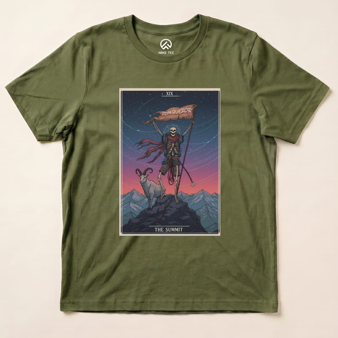 Graphic t-shirt featuring the "Summit Tarot Card Shirt" design with a skeleton holding a flag that says "Conqueror" among mountains.