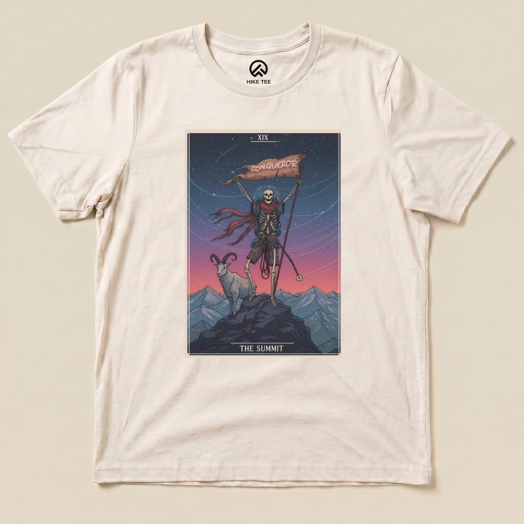 The graphic t-shirt features a skeleton in a cape holding a flag that reads "CONQUEROR" against a mountain backdrop, titled "Summit Tarot Card Shirt.