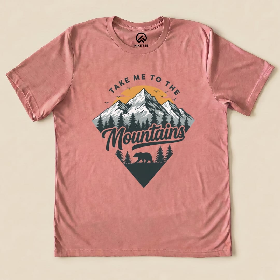 The graphic t-shirt features a design with mountains, trees, and a bear, along with the phrase "Take Me To The Mountains.