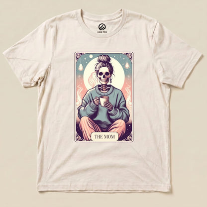 A graphic t-shirt features a whimsical design of a skeleton holding a mug, with the text "THE MOM" below the image.