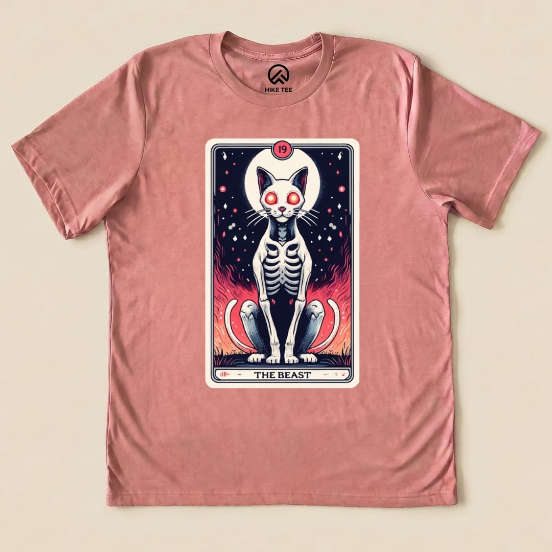 A graphic t-shirt featuring "The Beast Tarrot Cat" design, showcasing a skeleton cat with glowing red eyes against a fiery background.