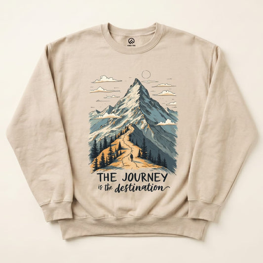 A beige sweatshirt featuring a mountain graphic and the slogan "THE JOURNEY is the destination," highlighting hiking themes.