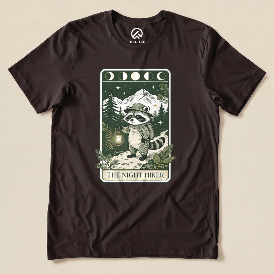 Brown The Night Hiker Shirt with a raccoon hiker with a lantern on a moonlit tarot card graphic