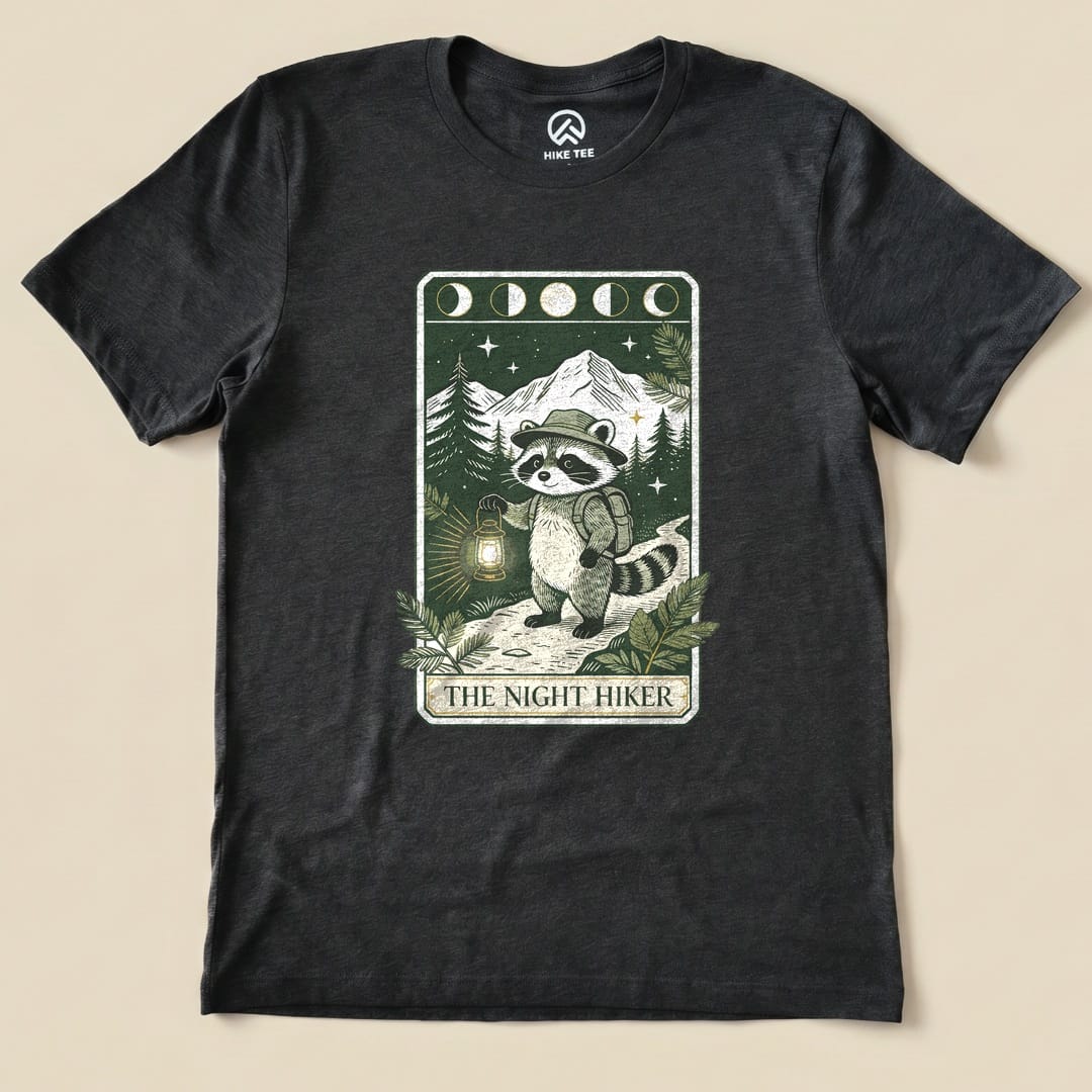 Dark Grey Heather The Night Hiker Shirt with a raccoon hiker with a lantern on a moonlit tarot card graphic