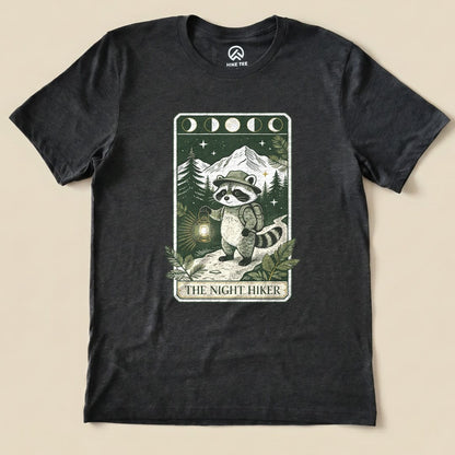 Dark Grey Heather The Night Hiker Shirt with a raccoon hiker with a lantern on a moonlit tarot card graphic