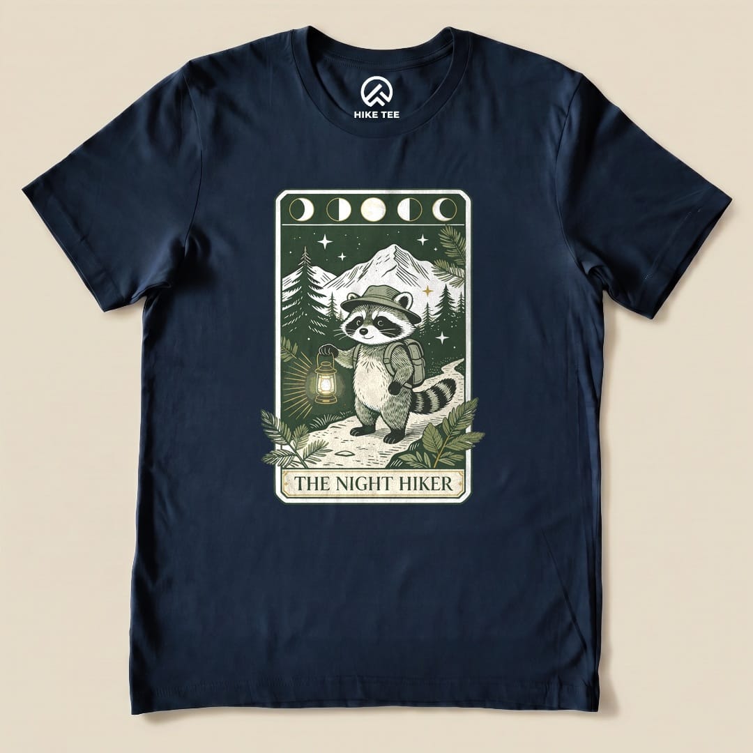 Navy The Night Hiker Shirt with a raccoon hiker with a lantern on a moonlit tarot card graphic
