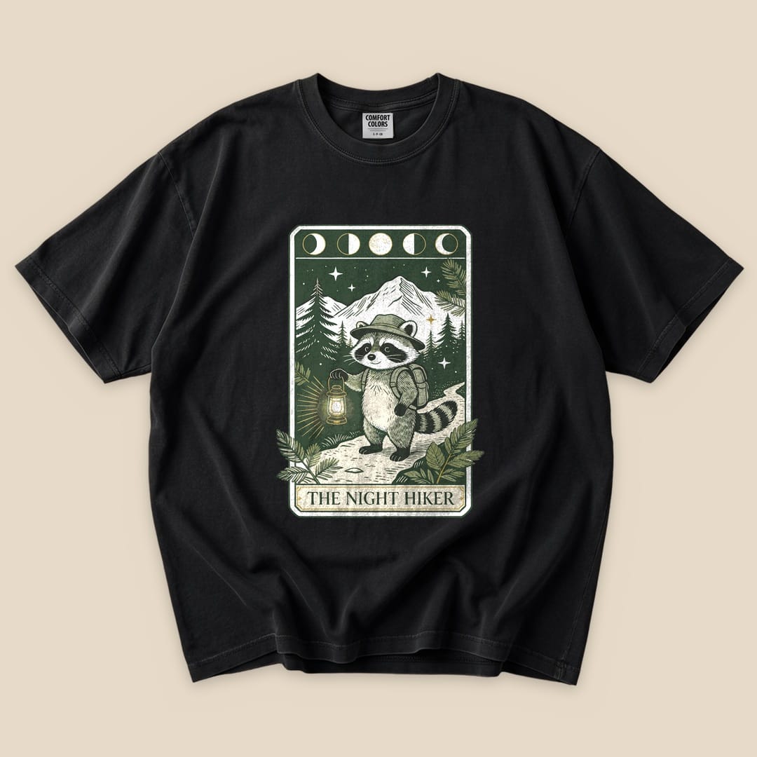 Black The Night Hiker T-Shirt with a raccoon hiker with a lantern on a moonlit tarot card graphic