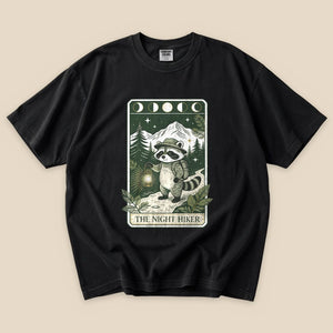 Black The Night Hiker T-Shirt with a raccoon hiker with a lantern on a moonlit tarot card graphic